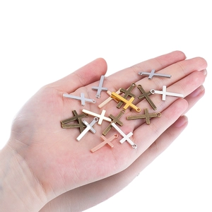 Hand holding vintage alloy cross pendants in silver and gold for DIY jewelry making