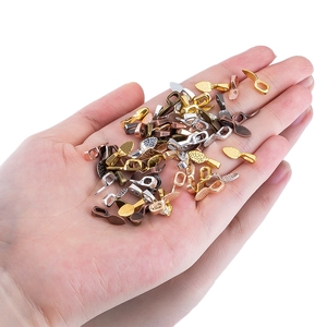 Mini vintage alloy shovel charms in assorted metallic colors held in hand for scale
