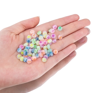 Vista macro de cuentas de letras acrílicas de colores en la mano para hacer joyas artesanales