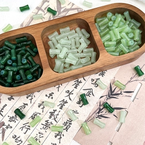 Detailed view of bamboo-shaped glass beads in various green tones for DIY jewelry making