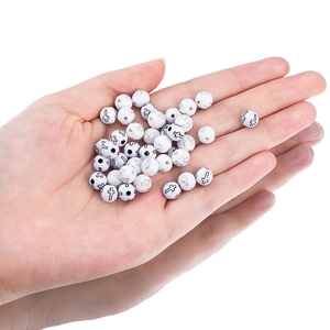 Primer plano de cuentas de acrílico blanco con cruces negras para creación de joyas