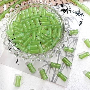 Macro shot of green bamboo-shaped glass beads for DIY jewelry on a traditional paper