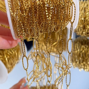 Macro detail of gold-plated stainless steel oval link chain on a spool for DIY jewelry
