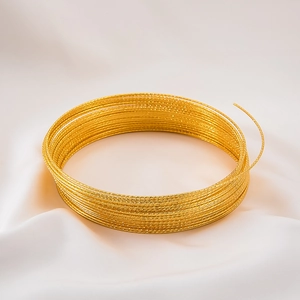 Macro detail of golden textured craft wire for DIY jewelry on white silk fabric