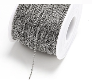 Macro shot of stainless steel silver jewelry chain on a white plastic spool for DIY crafting