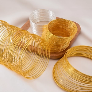 Macro shot of multi-layered sparkling gold and silver metal wire bracelets on a wooden tray