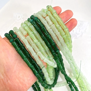 Detailed view of bamboo-shaped glass beads in various green gradients for DIY jewelry