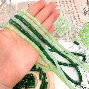 Detailed view of bamboo-shaped glass beads in various green tones for DIY jewelry making