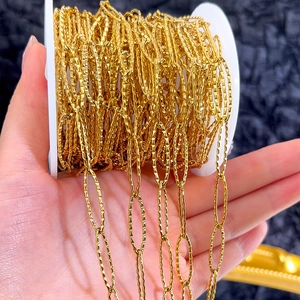Macro shot of gold-plated stainless steel paperclip chain with textured links on a spool