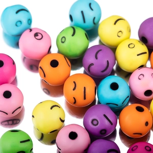 Vista macro de cuentas acrílicas de colores con caras sonrientes para joyería hecha a mano