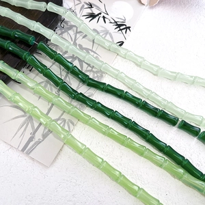 Detailed view of bamboo-shaped glass beads in various shades of green for DIY jewelry