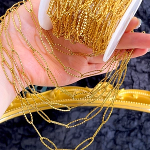 Detail of gold diamond-cut chain link with textured surface on a white spool