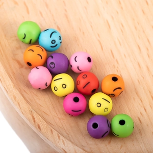 Cuentas acrílicas de colores con caritas sonrientes en bandeja de madera para bricolaje