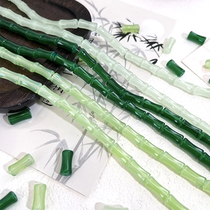 Close-up of bamboo-shaped glass beads in various green tones for DIY jewelry crafting