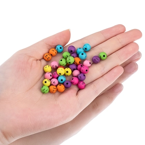 Cuentas acrílicas de colores con caritas para joyas DIY sostenidas en la mano
