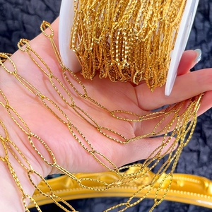 Macro detail of gold stainless steel diamond-cut oval link chain on a white spool
