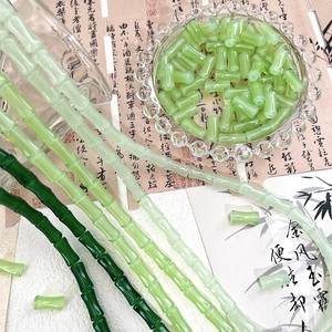 Detailed view of bamboo-shaped green glass beads with traditional Chinese calligraphy background