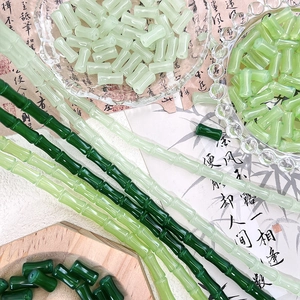 Macro shot of bamboo-shaped green glass beads on a wooden tray with a vintage paper background