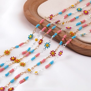 Bohemian daisy anklet with colorful beads and enamel flowers on a wooden tray