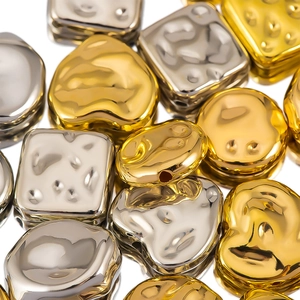 Makroaufnahme von unregelmäßigen Gold- und Silberherzperlen mit Hammerschlag für DIY Schmuck