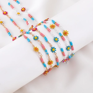 Close-up of colorful daisy enamel charms and beads on gold and silver anklet chains