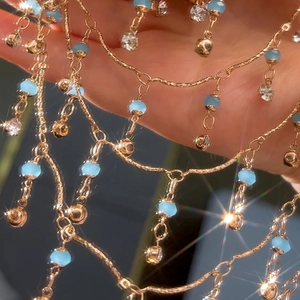 Nahaufnahme der goldenen Fransenkette mit hellblauen Perlen und Kristallen
