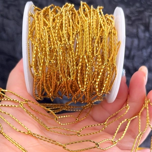 Macro detail of textured gold stainless steel jewelry chain on a white plastic spool
