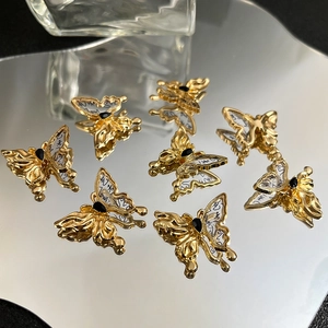 Nahaufnahme goldener Schmetterlingsanhänger mit Kalligraphie-Flügeln und schwarzem Stein