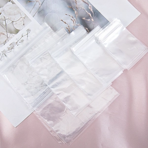 Detailed view of various sizes of transparent PE zip lock bags on a pink silk background