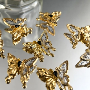 Makro-Detail von goldenem Schmetterlingsanhänger mit schwarzem Edelstein und Kalligraphie
