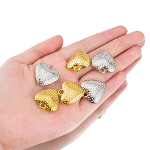 Detail of heart pendants with dotted texture in gold and silver plating on palm