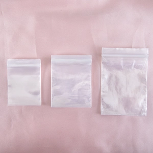 Three sizes of transparent PE plastic self-sealing storage bags on pink satin background