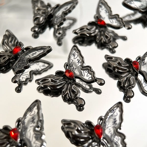 Makrodetail von Tinten-Schmetterlingsanhängern mit schwarzem Metallrahmen und rotem Tropfenkristall