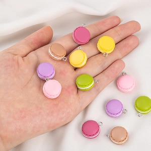 Nahaufnahme bunter Harz-Macaron-Anhänger in der Hand für DIY-Schmuckherstellung