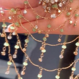 Detailansicht der mehrlagigen Goldkette mit grünen Perlen und funkelnden Kristallen