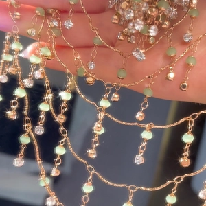 Detail von 4mm grünen Kristallperlen und Goldquasten an einer handgefertigten Kette