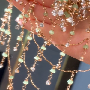 Detail einer rosévergoldeten Quastenkette mit grünen Perlen und funkelnden Strasssteinen