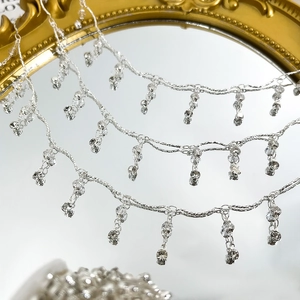 Makrodetail der 4mm Kristallperlenkette mit silbernen Quasten auf einem Goldspiegel