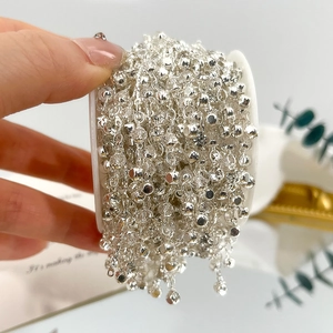 Makroaufnahme einer 4mm silbernen DIY-Kristallperlenkette auf weißer Spule für Schmuck