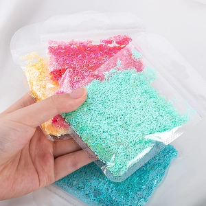 Primo piano di paillettes per nail art a forma di cuore in bustine gialle, rosa, menta e blu