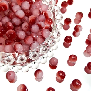 Macro detail of 8mm gradient glass beads with red and pink tones for DIY jewelry making