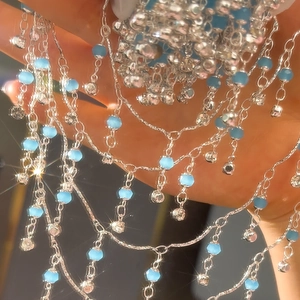 Makroansicht einer 4mm blauen Kristallperlenkette mit funkelnden Silberanhängern