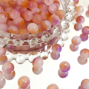 Macro shot of 8mm pink and orange gradient Czech glass beads in a textured glass bowl