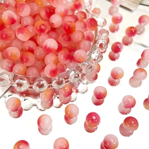 Macro detail of 8mm pink and red gradient Czech glass beads in a decorative glass bowl