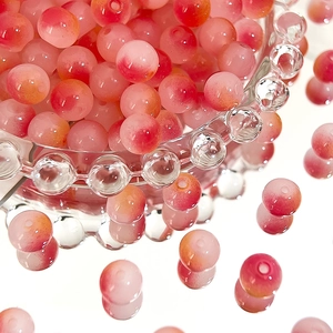 Detailed view of 8mm pink and red gradient Czech glass beads in a glass bowl for DIY jewelry