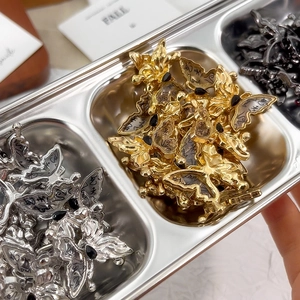 Makroaufnahme von Schmetterlings-Anhängern in Gold, Silber und Schwarz für DIY-Schmuck