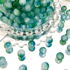 Macro shot of blue-green gradient 8mm glass beads with precise center holes for DIY crafting