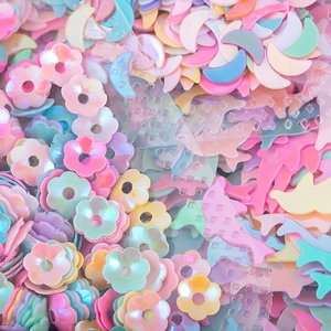 Vista macro di paillettes per unghie color macaron in forme di stelle cuori e delfini perlati