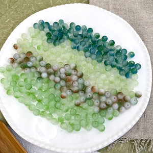 Polished 8mm gradient Czech beads in green and blue tones displayed on a white porcelain dish