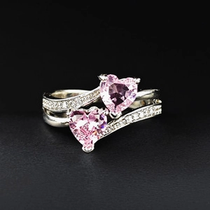 Macro detail of silver ring featuring dual pink heart-shaped stones and pavé diamonds